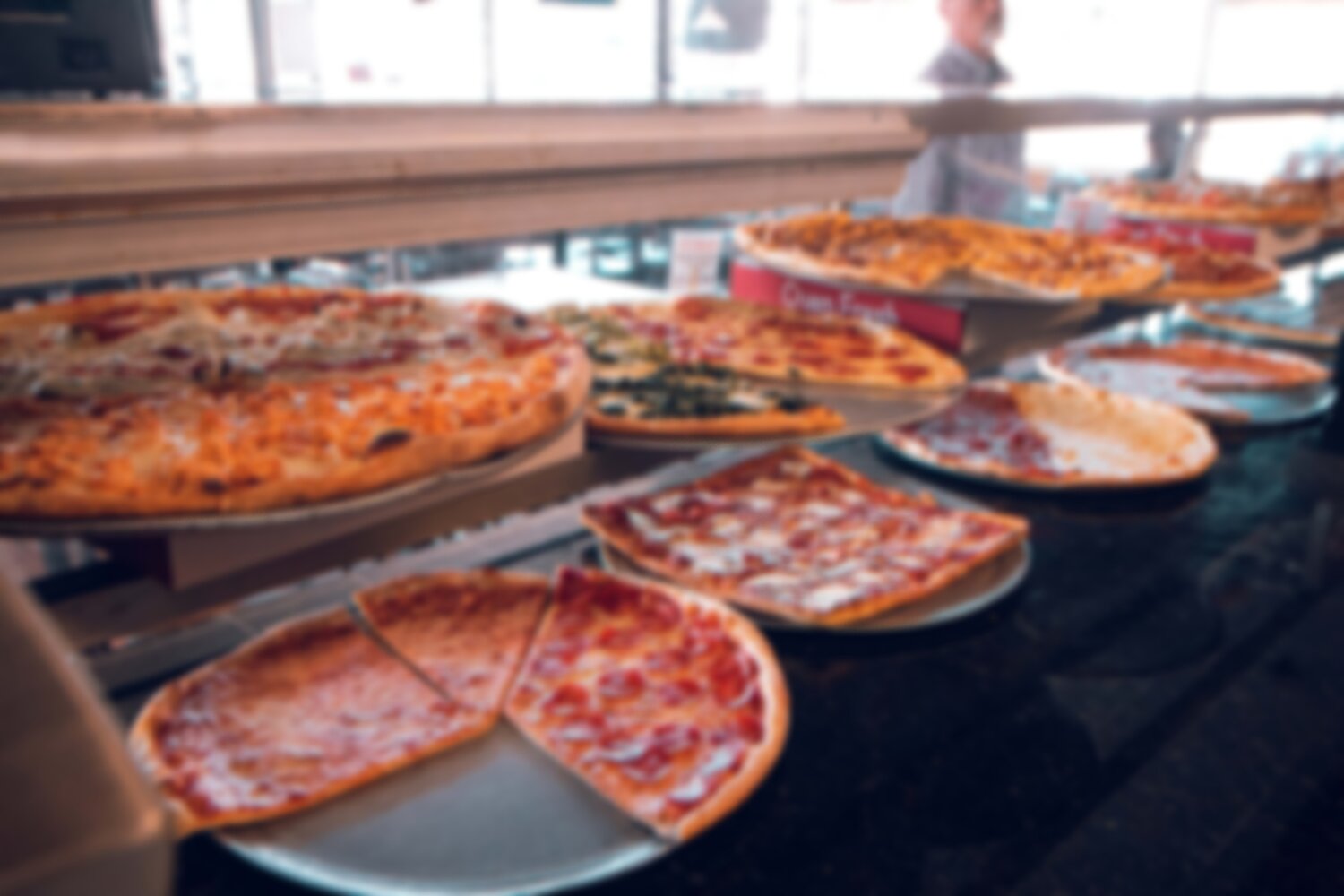 Pizzas on a counter in a restaurant.